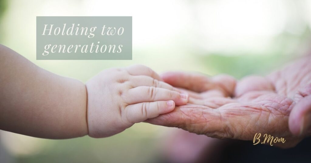 A child’s hand resting on an older person’s hand, with text reading: “Holding two generations.”
