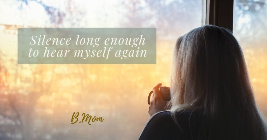 A mother sitting quietly by a window, reflecting on silence and personal space in motherhood.
